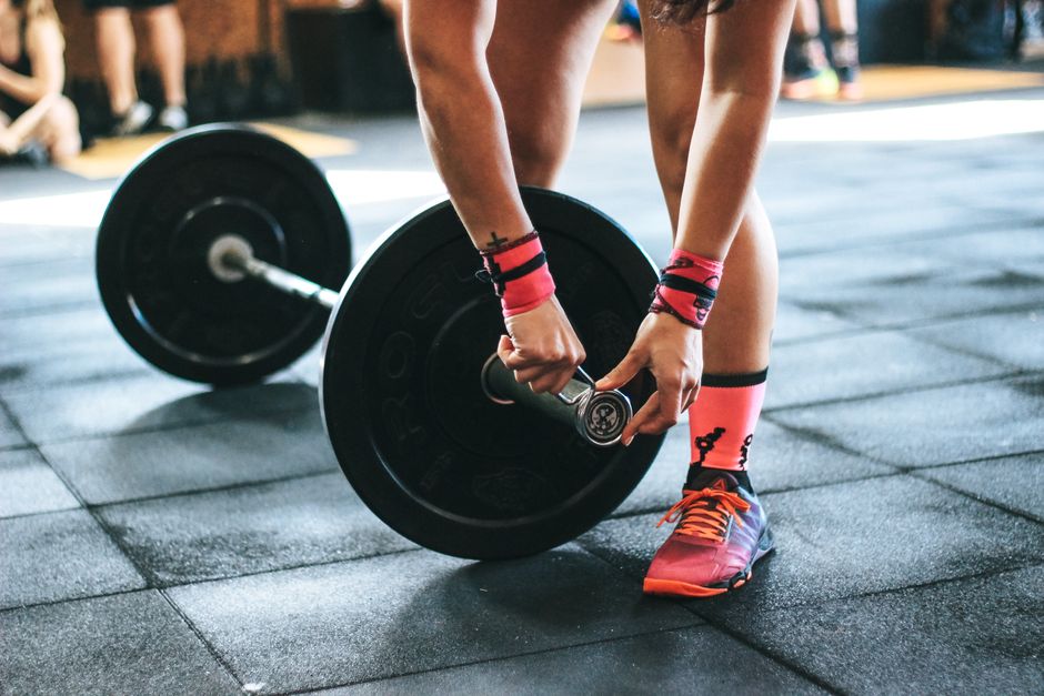 Athlete tightening barbell plates in a gym.