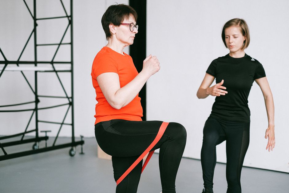 Personal trainer guiding woman with resistance band.
