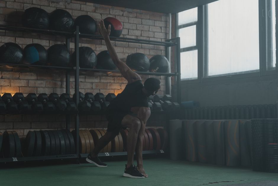 Man performing dynamic stretching in gym.