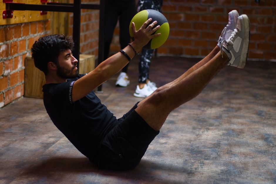 Focused man performing core exercises with a medicine ball
