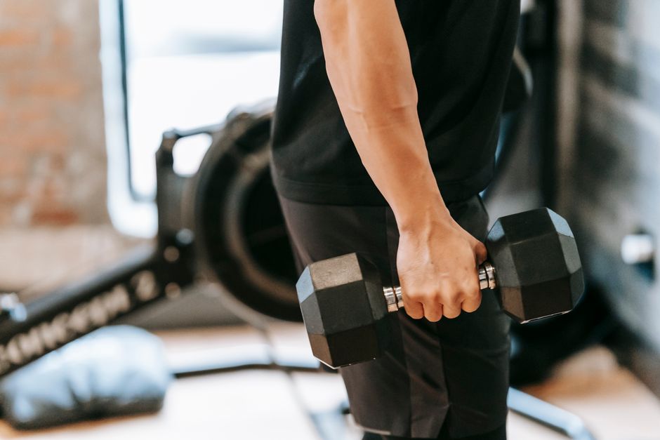 Muscular male in black activewear lifting heavy weight in spacious fitness studio